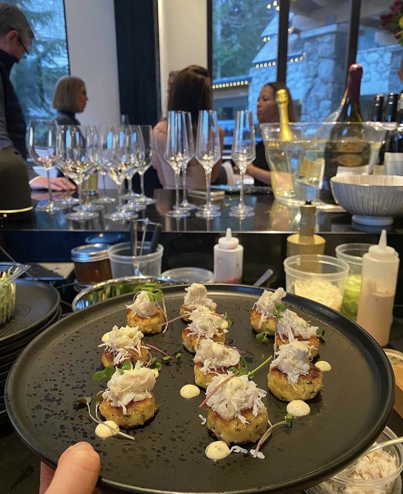 Dungeness crab cakes topped with fresh crab and micro greens on a black platter