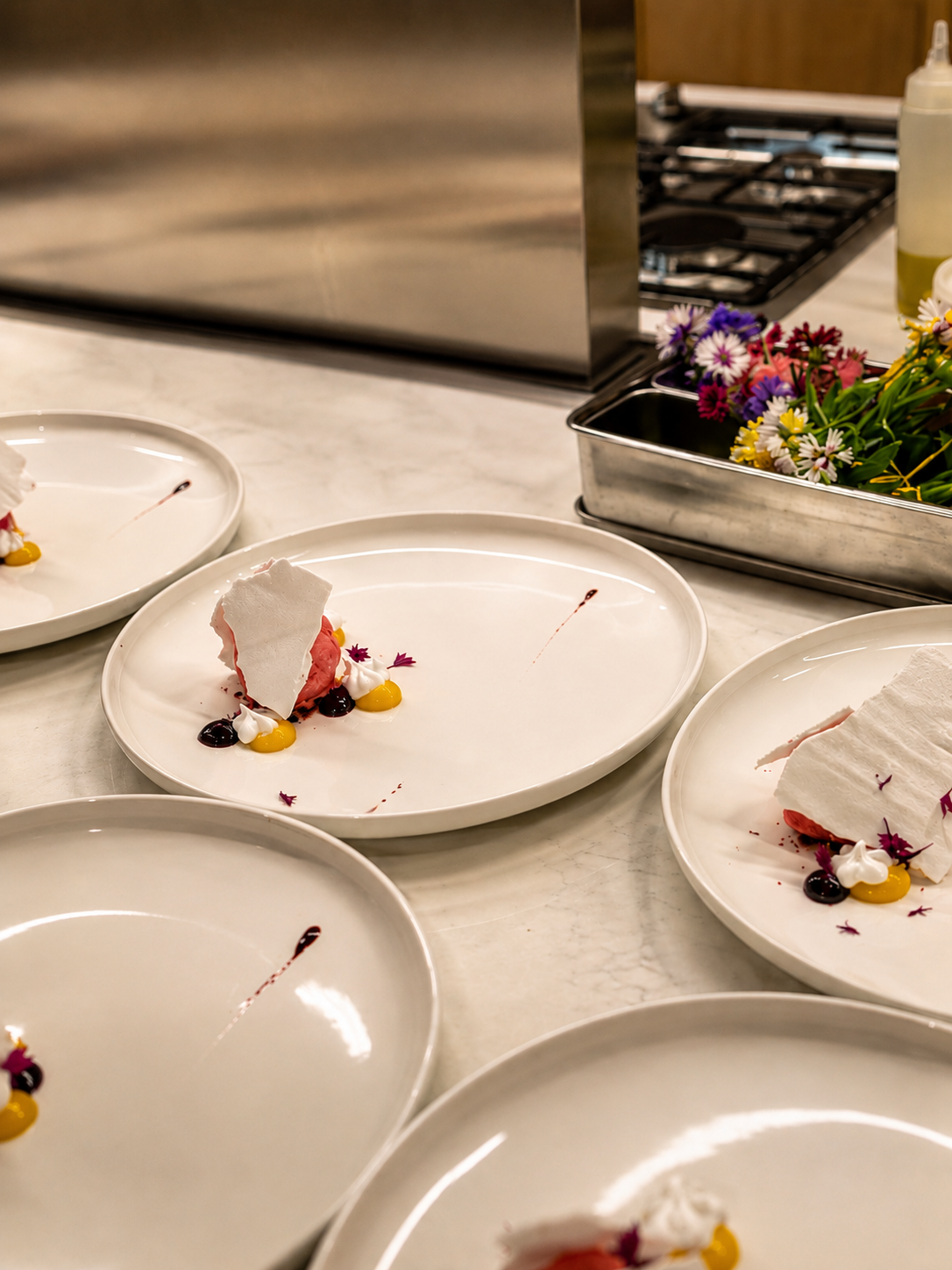 Dessert plates with meringue, berries and citrus being finished in the kitchen