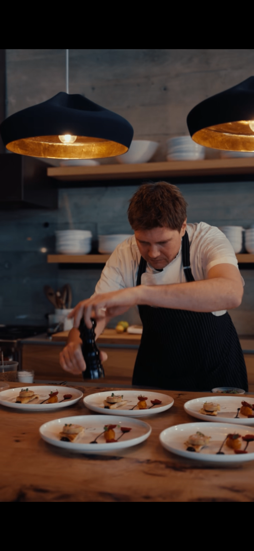 Chef Michaël plating a multi-course dinner under warm pendant lights