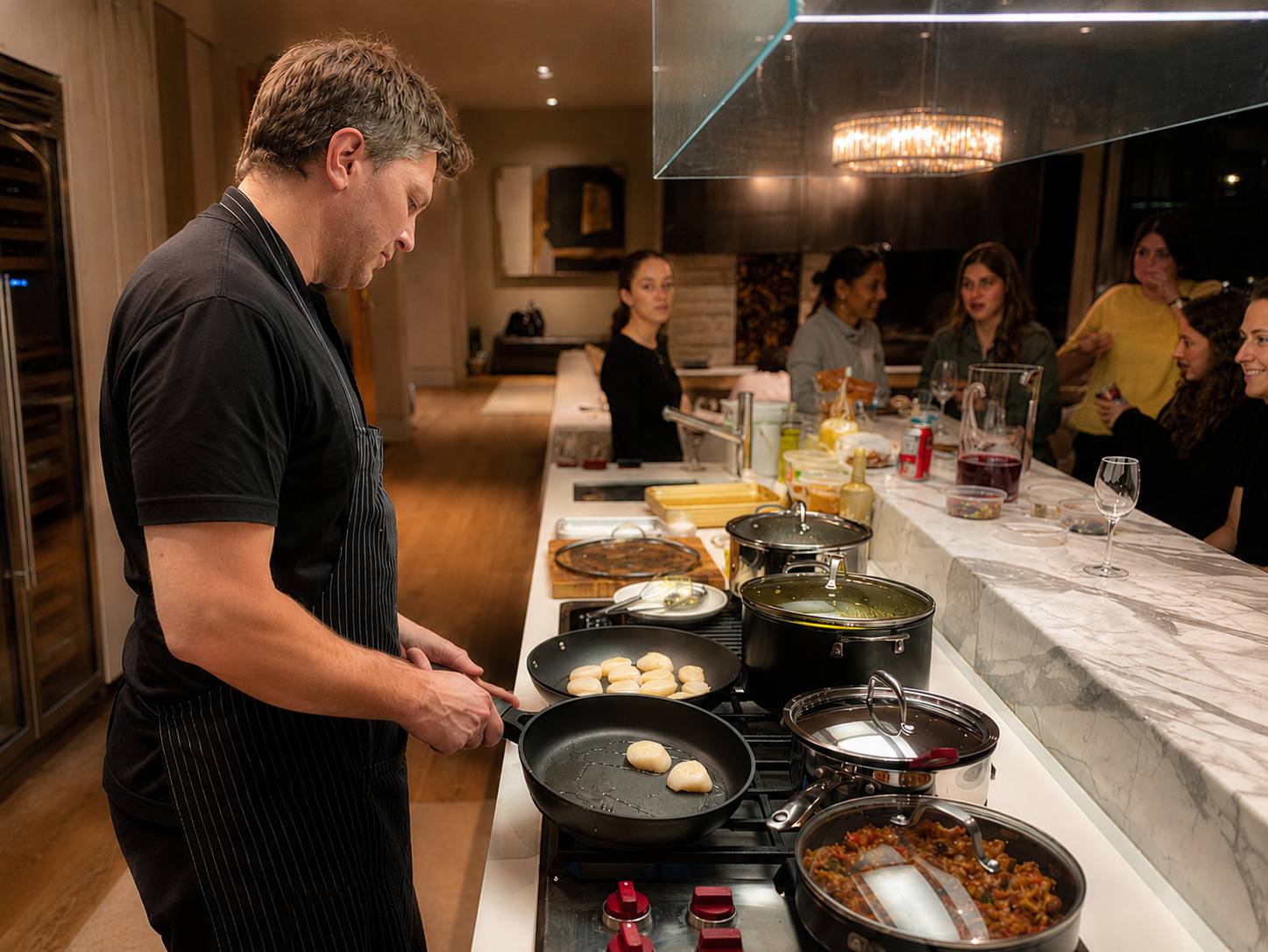 Chef Michaël searing scallops on the stovetop while guests watch from the kitchen bar