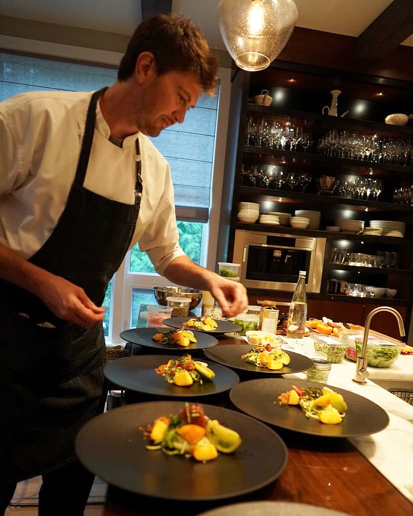 Chef Michaël in a white chef jacket plating a course in the kitchen